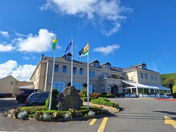 Picture of Ballyliffen Hotel & Spa with decorated green in front with three flags.